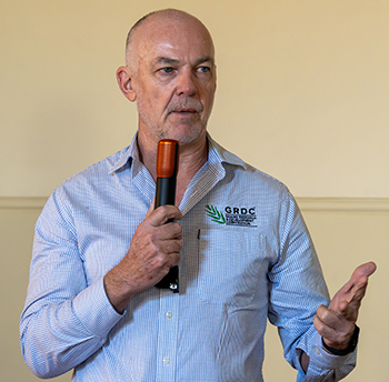 Man in blue GRDC collared shirt holding a microphone.