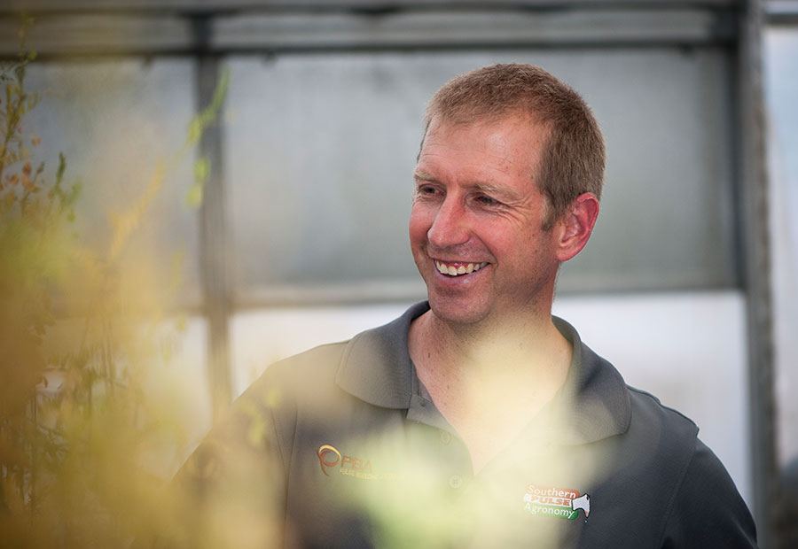 Smiling man with plant obscuring photo