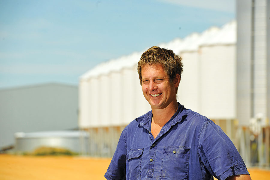 Smiling man standing in front of silos