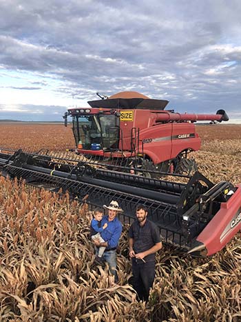 Andrew Milla, holding his son Cooper, with contract harvester Joel Rauchle. PHOTO Margie Milla