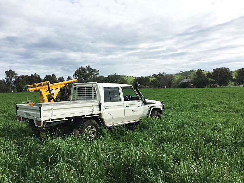 white ute in a field with a yellow soil drill rig on the tray