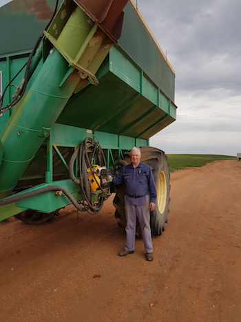 Farmer standing beside chaser bin fitted with fire-fighting unit.