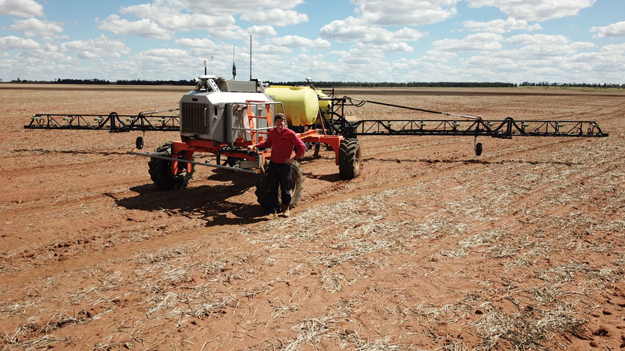 Tom Coggan in an empty paddock standing with his Weedit.