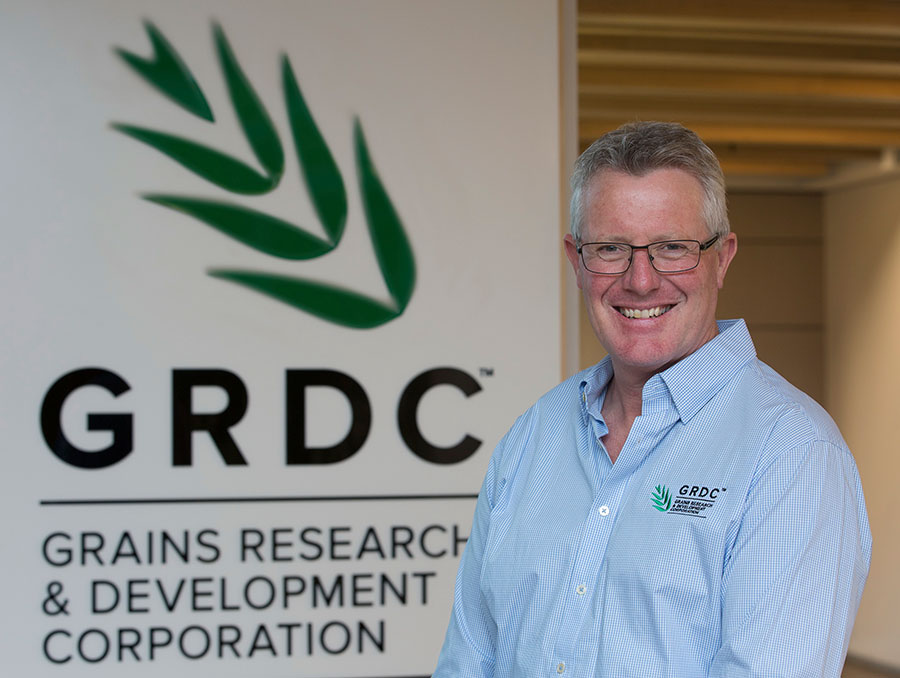 Man in blue shirt standing in front of GRDC sign