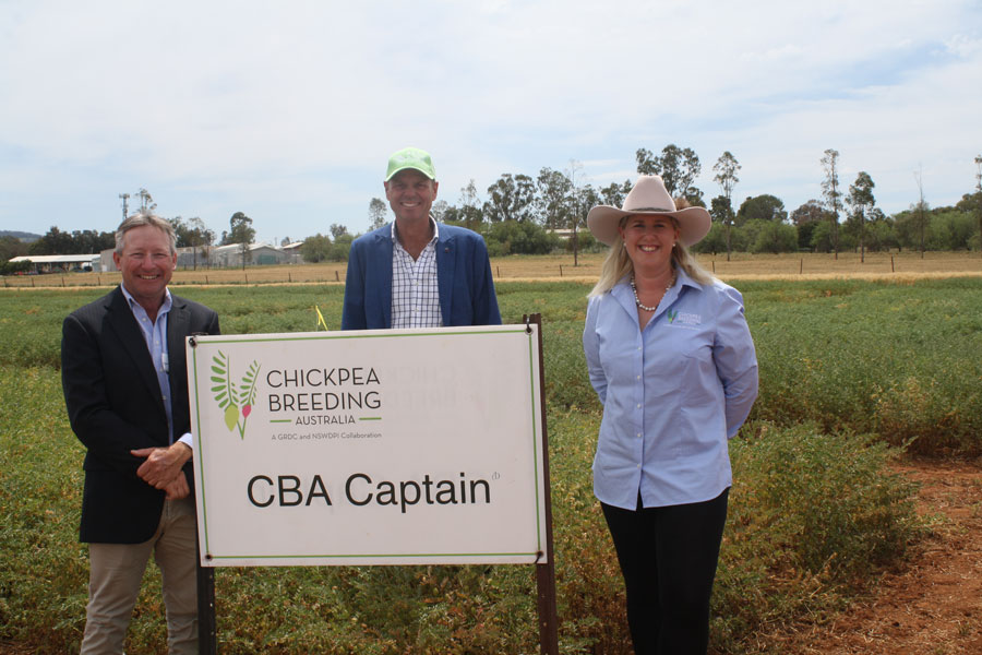 People standing in a field behind a billboard with CBA Captain written on it