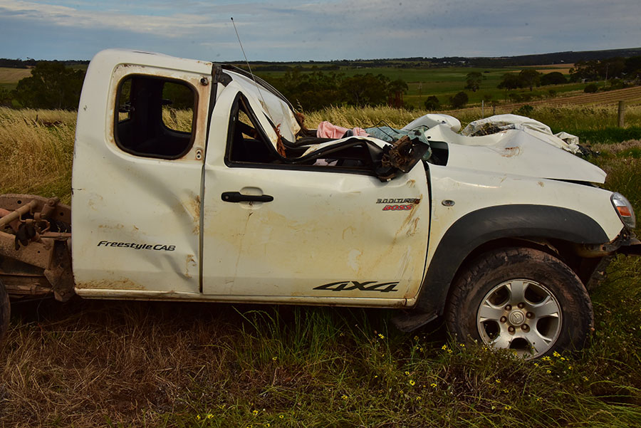 Photo of ute in a field with it's roof caved in after rolling.