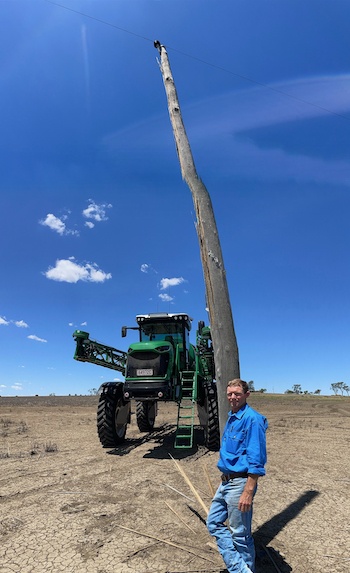 Phil Crocker standing beside a power pole with his self-propelled sprayer