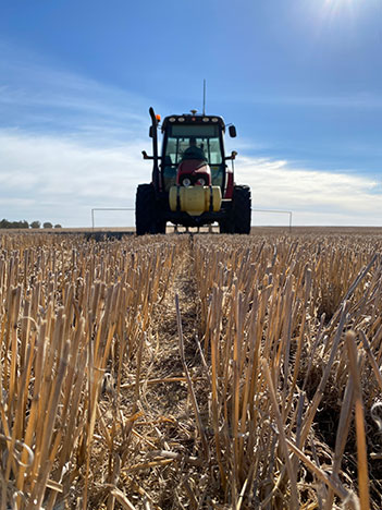 Photo of tractor in field of stubble.