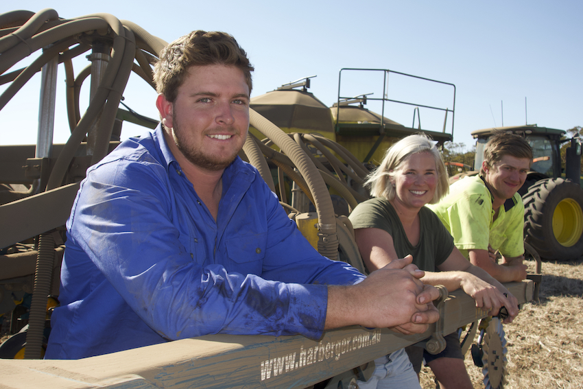 Alex Boehm, Lou Flohr and Damon Perks leaning on the seeder