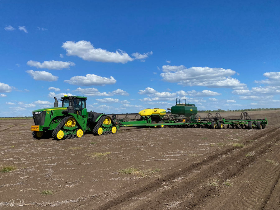 Photo of a green tractor in a paddock towing an attachment.